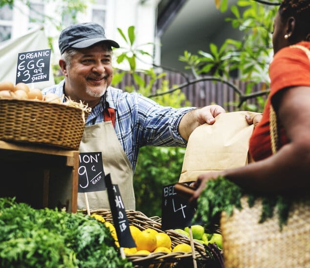 Greengrocer selling organic fresh agricultural product at farmer market