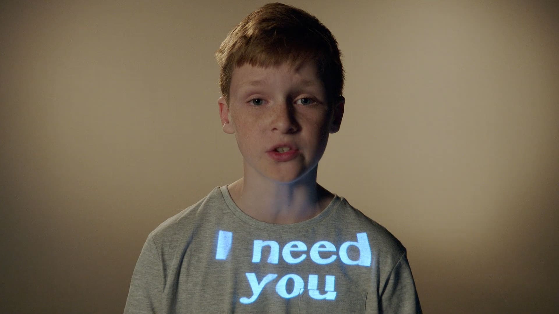 Young boy with the words I need you projected onto his t-shirt